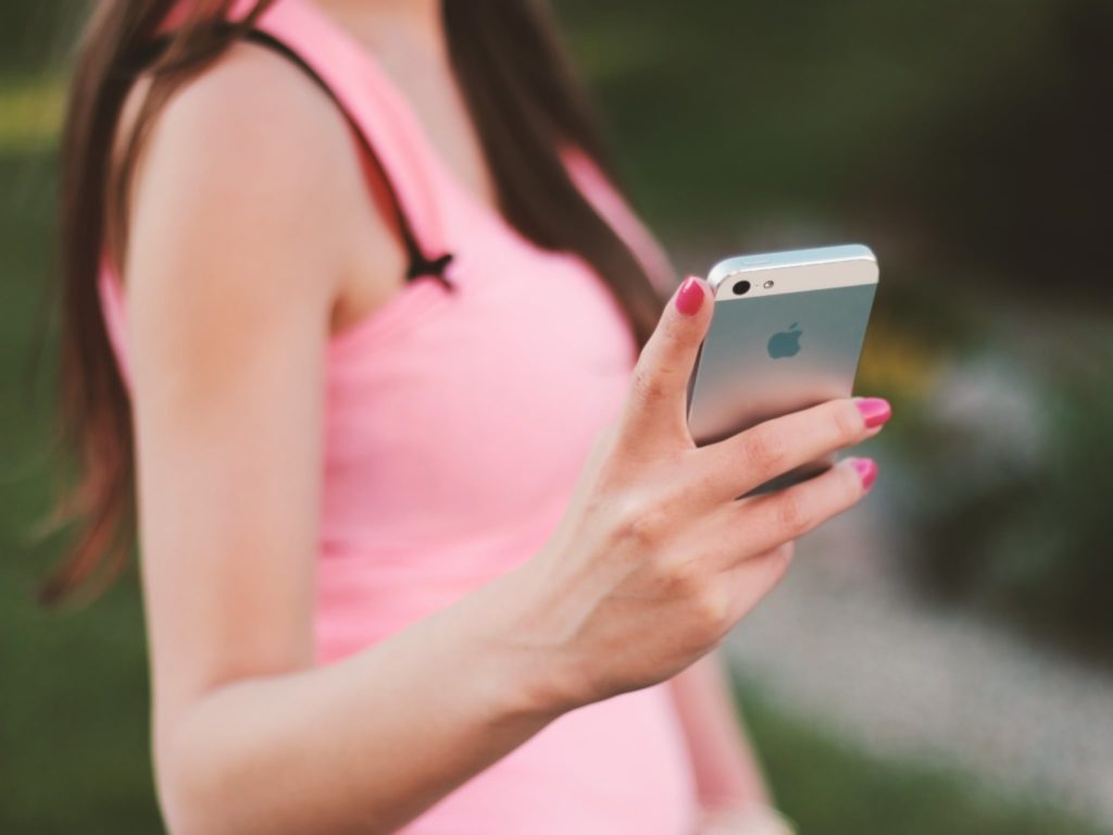girl in pink skirt holding iphone